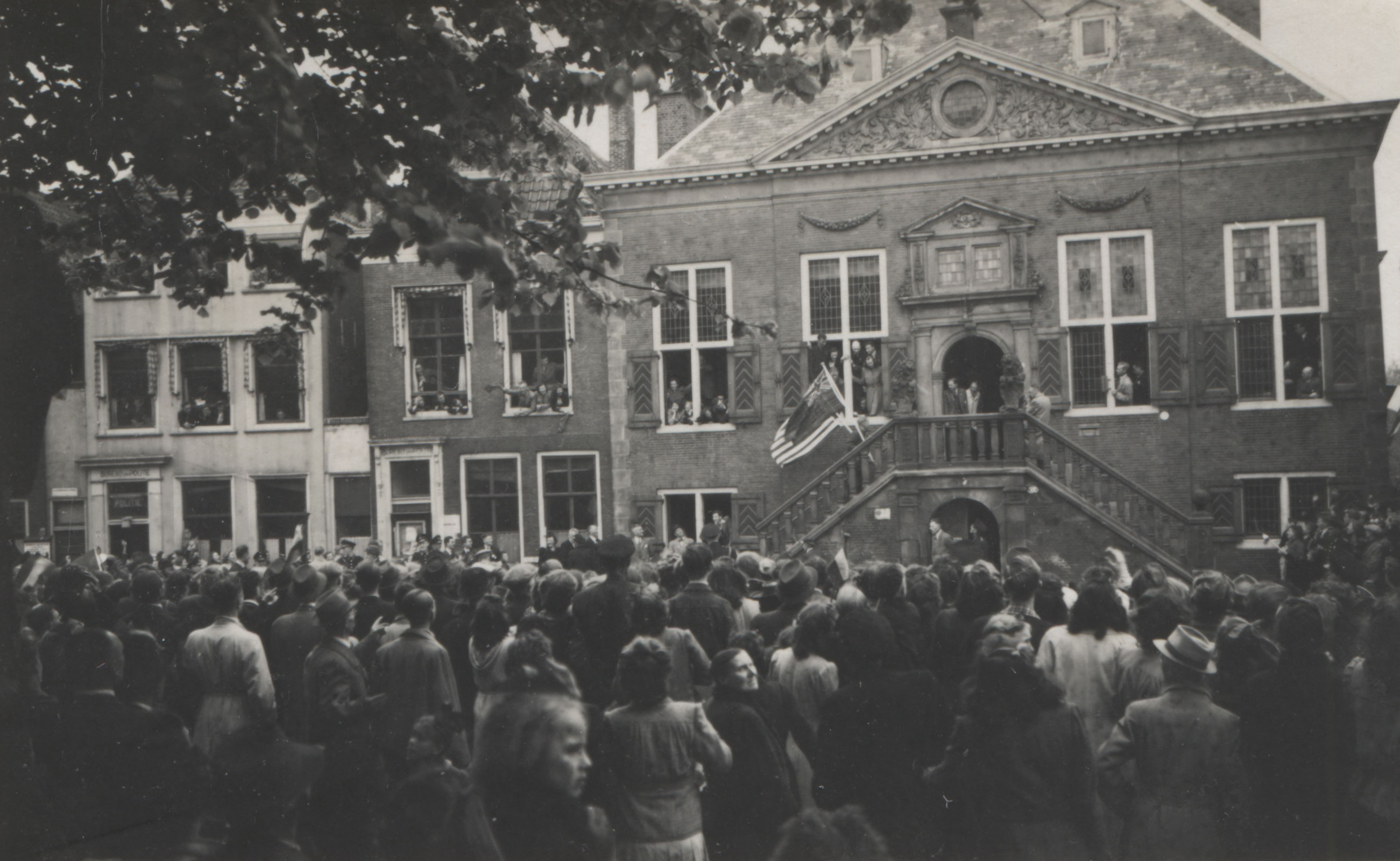 Malcolm Edwardsen, een van de drie ondergedoken Amerikaanse vliegeniers, loopt de trap op van het stadhuis met de Amerikaanse en Britse vlag. Even later hangen de twee vlaggen uit het torentje van het stadhuis. 